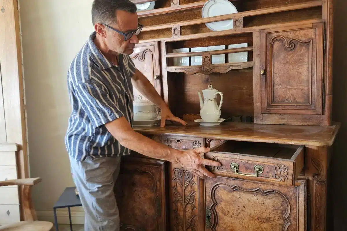 Antiquaire examinant l'intérieur d'un meuble ancien pour évaluer son état
